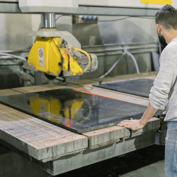 Skilled stonemason working on a marble slab in a factory, expertly cutting and polishing the stone to create custom pieces for luxury interiors